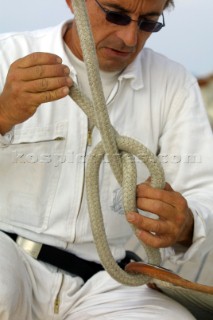 Crew member ties a halyard to the head of a sail with a bowline