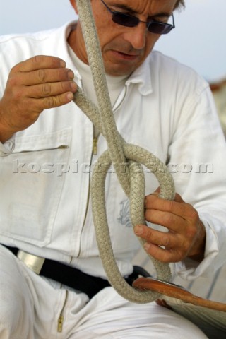 Crew member ties a halyard to the head of a sail with a bowline