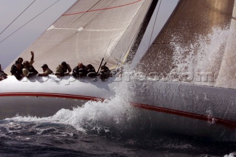 Crew on windward rail of racing yacht in choppy seas 
