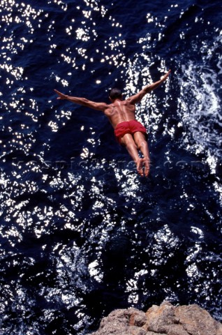 Musto man high diving into the sea from a cliff in Majorca 