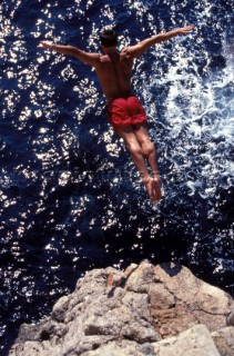 Musto man high diving into the sea from a cliff in Majorca