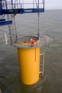 Construction of Windfarm on the Kentish flats in the Thames estuary off Whitstble Kent. Onboard the construction ship Resolution during the foundation process, where the Monopile is hammered in to the seabed with a hydraulic hammer and the transition piece lowered onto the monopile, picture shows monopile being craned into place ready for piling into seabed
