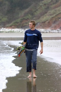 Man walking along Whitecliff Bay Beach with Kiteboard, Isle of Wight