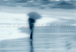 Figure under umbrella on beach