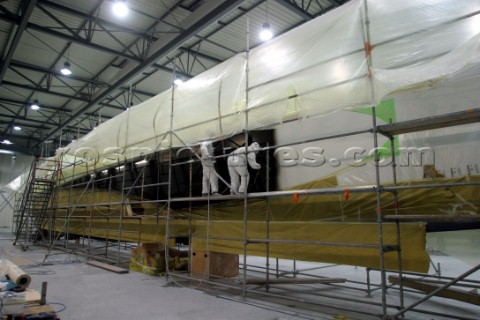 Boatyard workers painting the topsides of a superyacht with a spray gun 