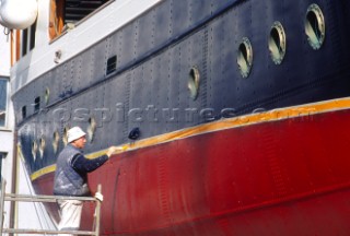 Man painting the hull of a large boat.