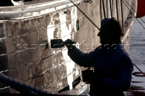 Silhouette of man painting hull of boat