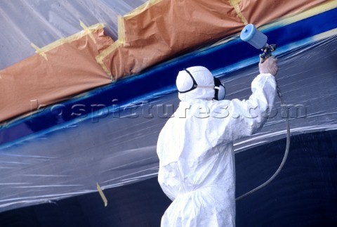 Man spray painting hull of yacht