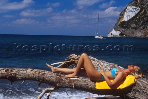 Woman sunbathing on tree branch 