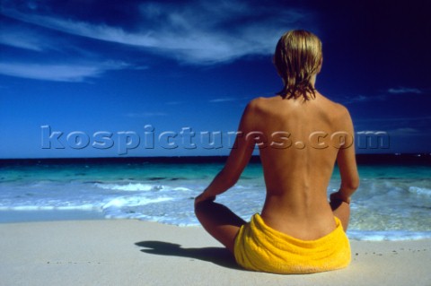Woman sitting on beach looking out to sea 