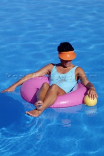 Woman floating on rubber ring in swimming pool