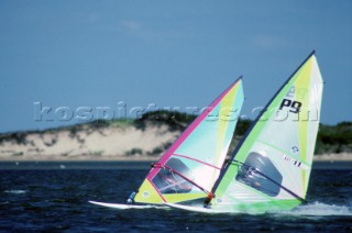 Two windsurfers racing in strong breeze