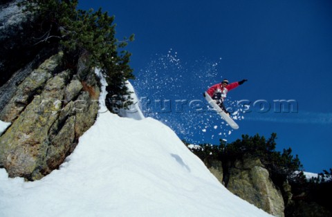 Snowboarder jumping off rocky outcrop 