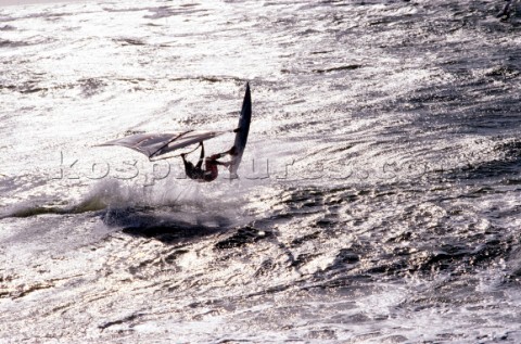 Silhouette of windsurfer jumping wave