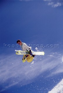 Snowboarder grabs board in mid jump.