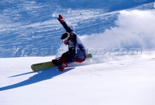 Snowboarder carving through fresh powder snow.
