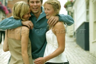 A man and two girls embrace on a cobbled street in Lymington, UK