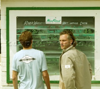 Two men check the weather forecast on a black board at a sailing club