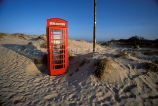Red telephone box on beach, Shell Bay, Poole, Dorset, UK