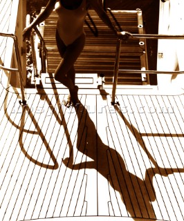 Shadow of woman in bikini on deck of superyacht