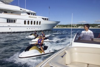 Jet skiers and tender driving passed anchored superyacht