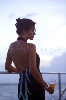 Woman on superyacht in evening dress with glass of wine