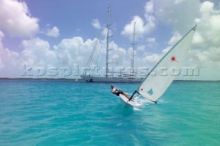 Sailing dinghy approaching anchored superyacht