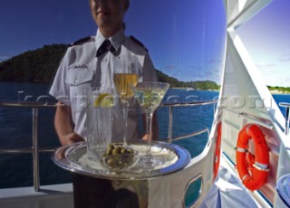 Reflection of superyacht stewardess with tray of cocktails