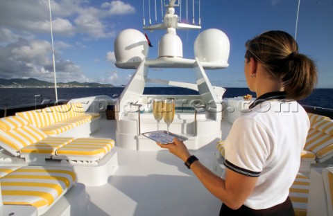 Superyacht stewardess with tray of champagne