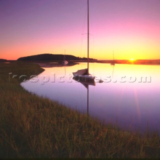 Sailing boat moored on still water at sunset