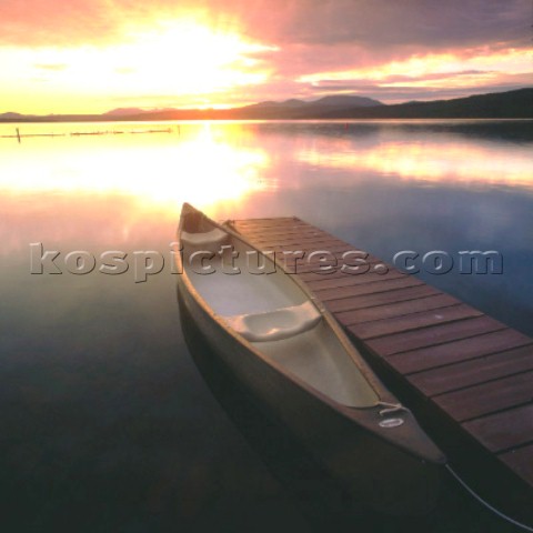 Canadian canoe moored to wooden jetty at sunset
