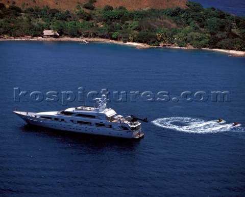 Superyacht at anchor in a tranquille bay with two recreational jet ski and water bike waverider