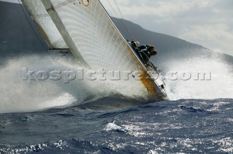 Crew on windward rail of yacht crashing through wave in choppy seas