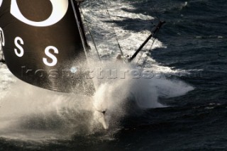 Open 60 racing yacht powering through rough seas in strong winds