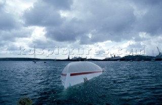 The Maxi yacht Drum owned by Simon Le Bon of Duran Duran lies upturned and capsized without its keel in Falmouth Harbour after the accident of the Fast race in 1985