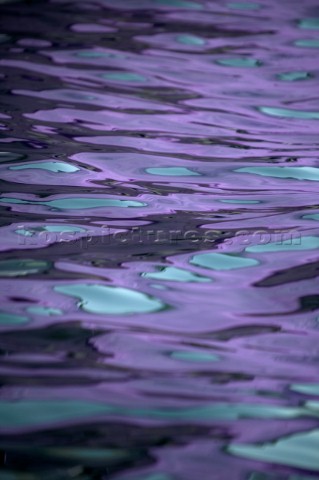 Texture on the water and reflection of a lilac purple and turquoise spinnaker of a sportsboat racing