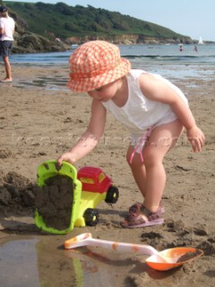Young girl toddler playing with toys in the sand on the beach