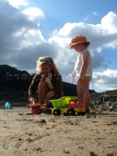 Young girl toddler playing with her mother on a sandy beach