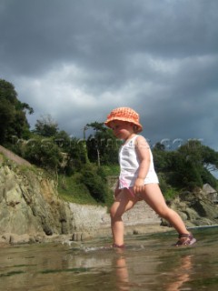 Young girl toddler paddling on a sandy beach