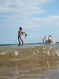 Children playing and paddling on a sandy beach looking for crustacea and crabs