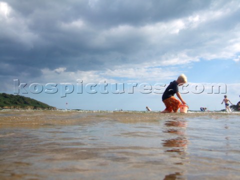 Children playing and paddling on a sandy beach looking for crustacea and crabs
