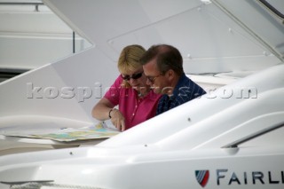 A couple on a powerboat use charts to plan their navigation before a voyage
