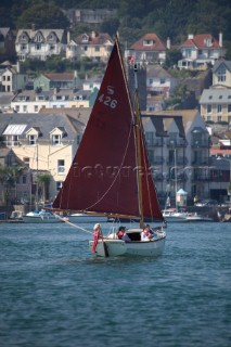 A Cornish Shrimper returns under brown sail to Dartmouth Harbour up the River Dart