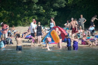 A sandy English beach in Salcombe Harbour busy with British holidaymakers playing and paddling in the sea