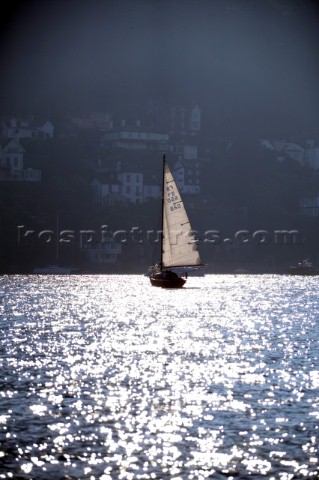 Cruising yacht sailing silhoutte against Dartmouth Harbour