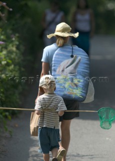 Lady and young boy heading for beach with boogy board and fishing net