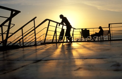 Silhouetted figures on deck of ferry Patras Greece