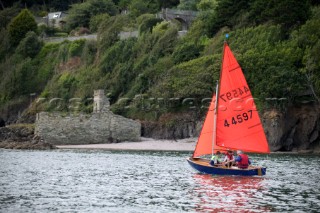 Sailing dinghy with orange sails close inshore