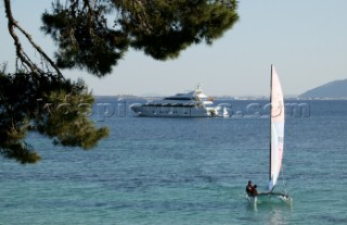 Hobie cat sailing dinghy and superyacht anchored in bay.  Formentor, Mallorca