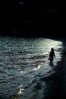 Silhouette of little girl holding bucket on beach